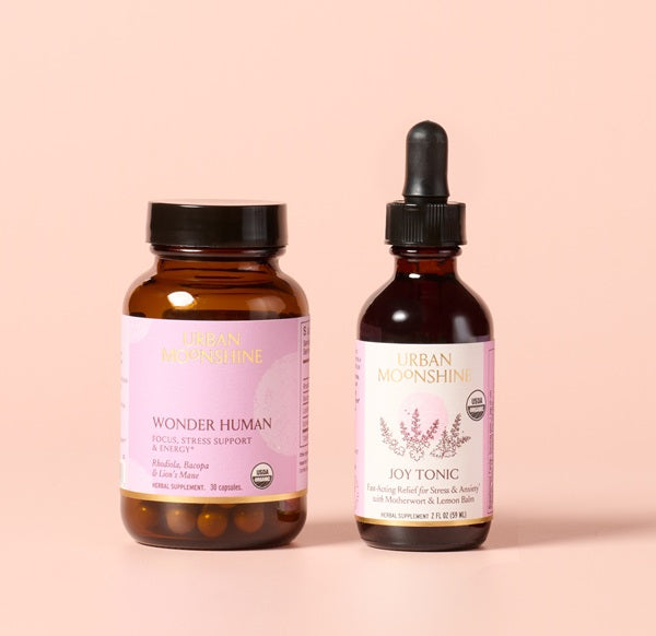 Two bottles of Urban Moonshine products on a pink background