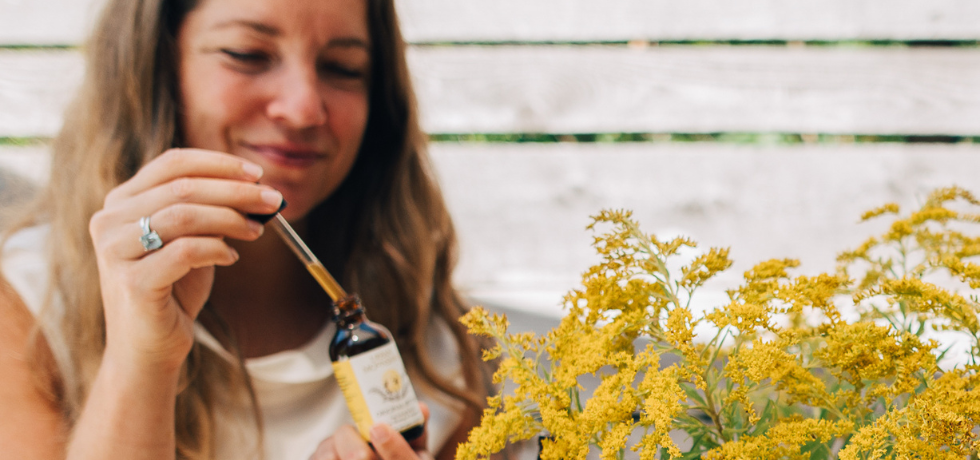 Woman holding original bitters bottle with goldenrod flowers