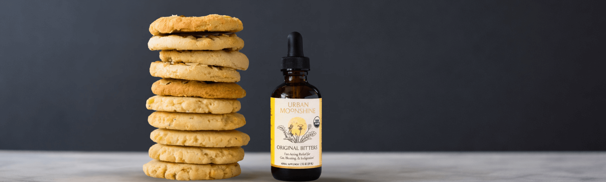 Bitters bottle with cookies on dark background