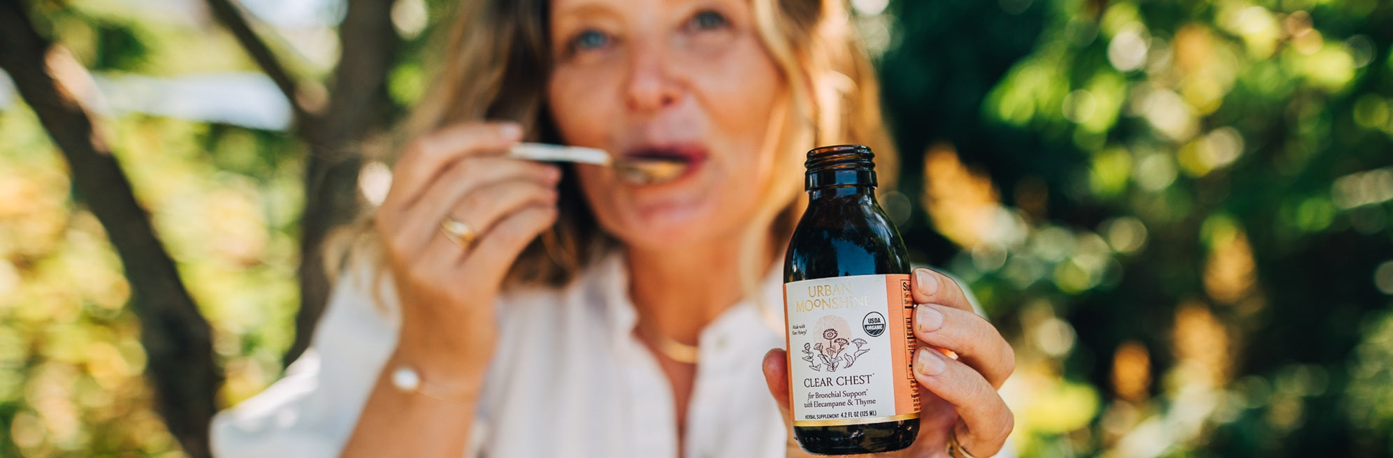 Jovial holding a bottle of Clear Chest with a blurred natural background