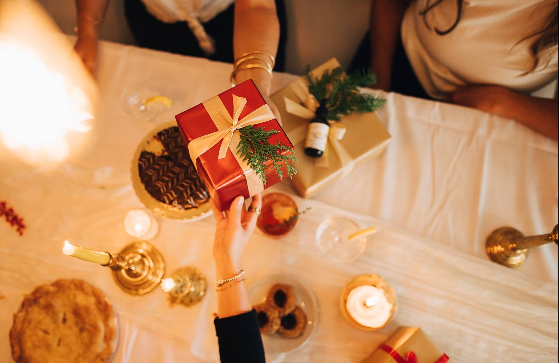 Decorative table setting with pies, candles, and small gift boxes on a white tablecloth.