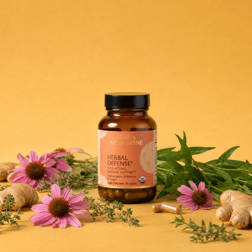 Herbal Defense capsule bottle with plant ingredients on an orange background