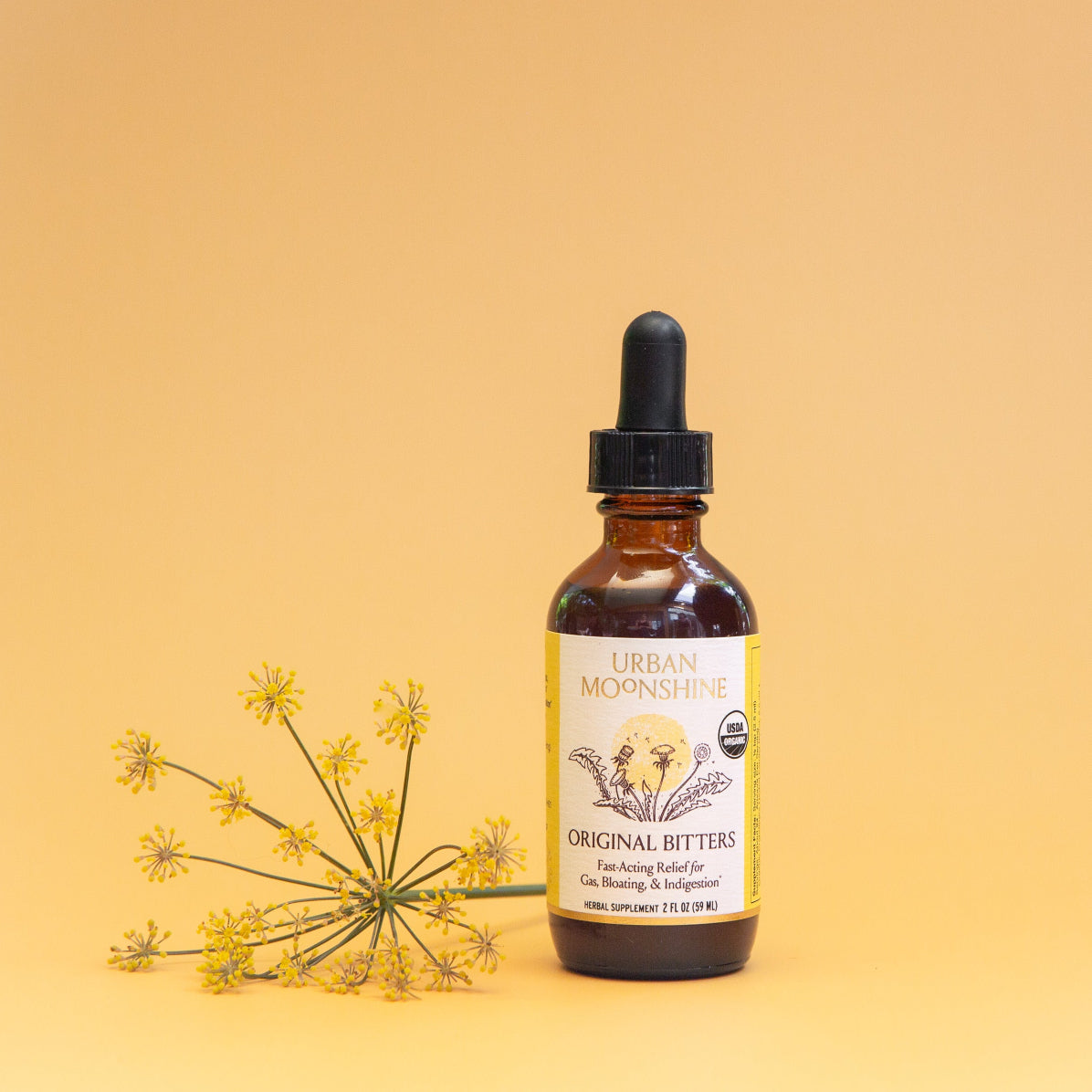 Bottle of Urban Moonshine Original Bitters on a yellow background with a small plant.