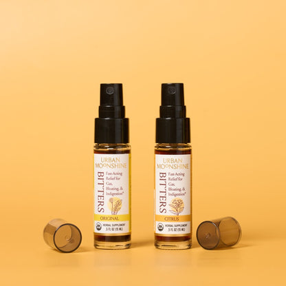 Two bottles of Urban Moonshine Bitters on a yellow background