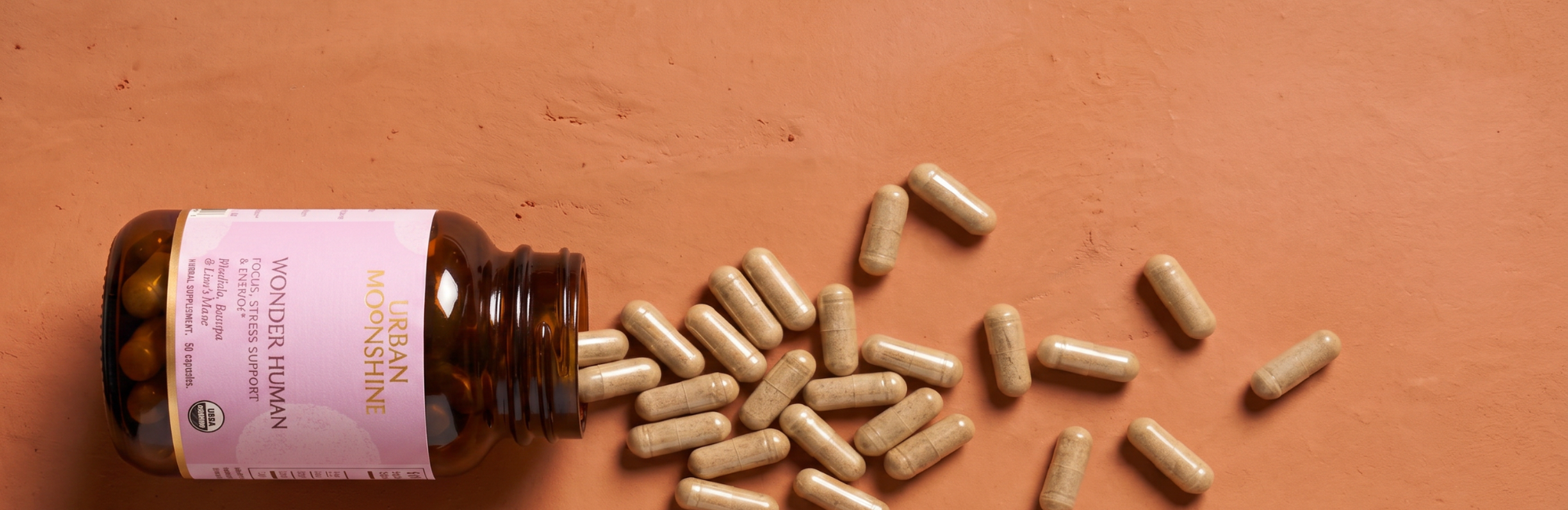 Bottle of Wonder Human with scattered capsules on an orange background