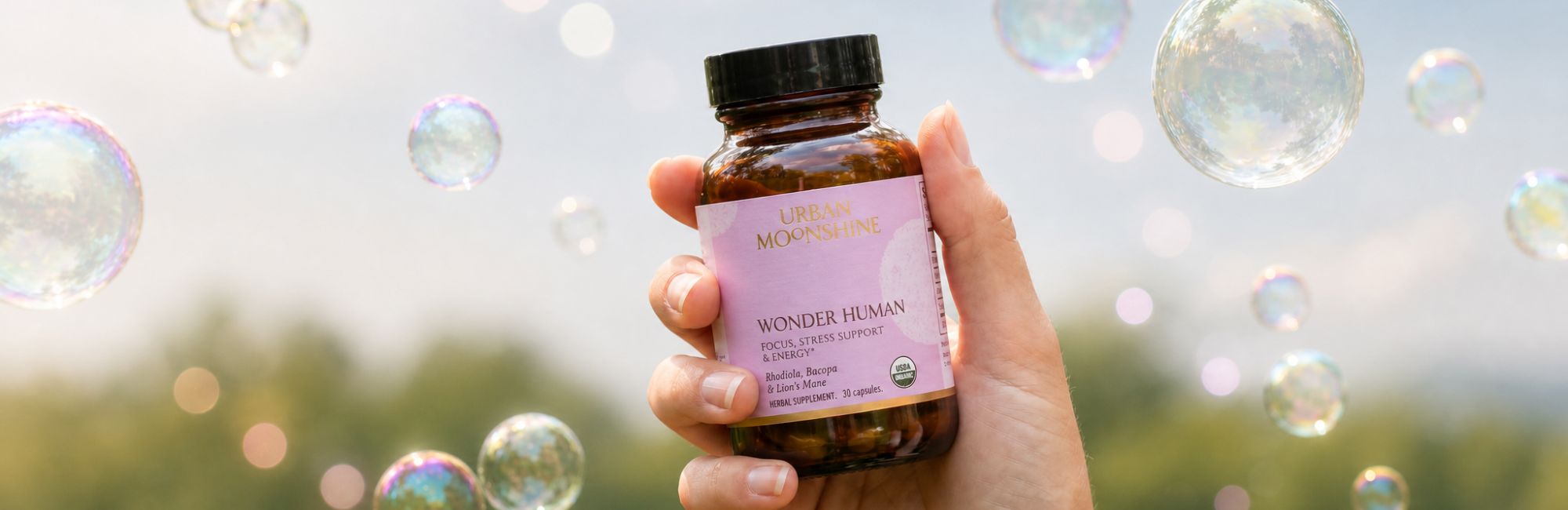 Hand holding a bottle labeled 'Wonder Woman' with bubbles in the background